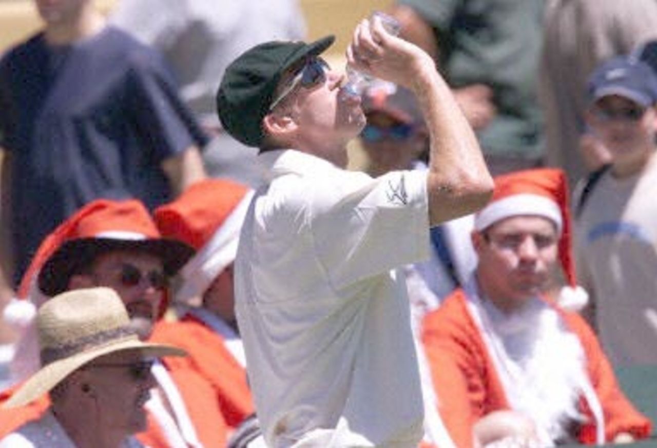Australian fast bowler Glenn McGrath has a drink watched by fans dressed as Santa Claus, during the first day of the third test against the West Indies at the Adelaide oval 15 December 2000. At lunch the West Indies are 2 for 61 runs, with Australia currently leading the five test series against the West Indies 2-0.