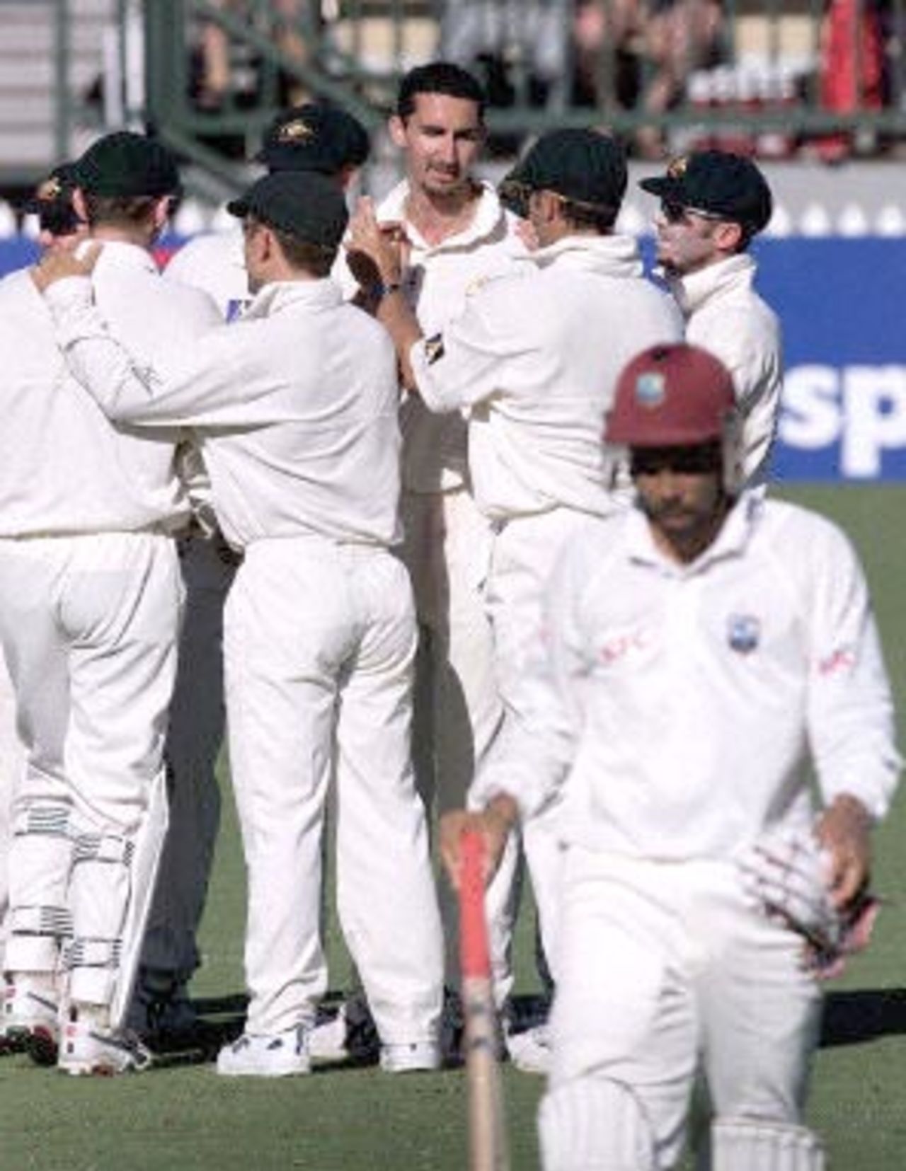 Australian fast bowler Jason Gillespie (3rd R, at back) is congratulated by teammates after taking the wicket of West Indies captain Jimmy Adams (leaving field) for 49 runs on the first day of the third test against the West Indies at the Adelaide oval 15 December 2000. Gillespie took all four wickets to fall, with the West Indies finishing the day on 4 for 274 runs, with Lara not out on 136 and Dillon not out on 3.