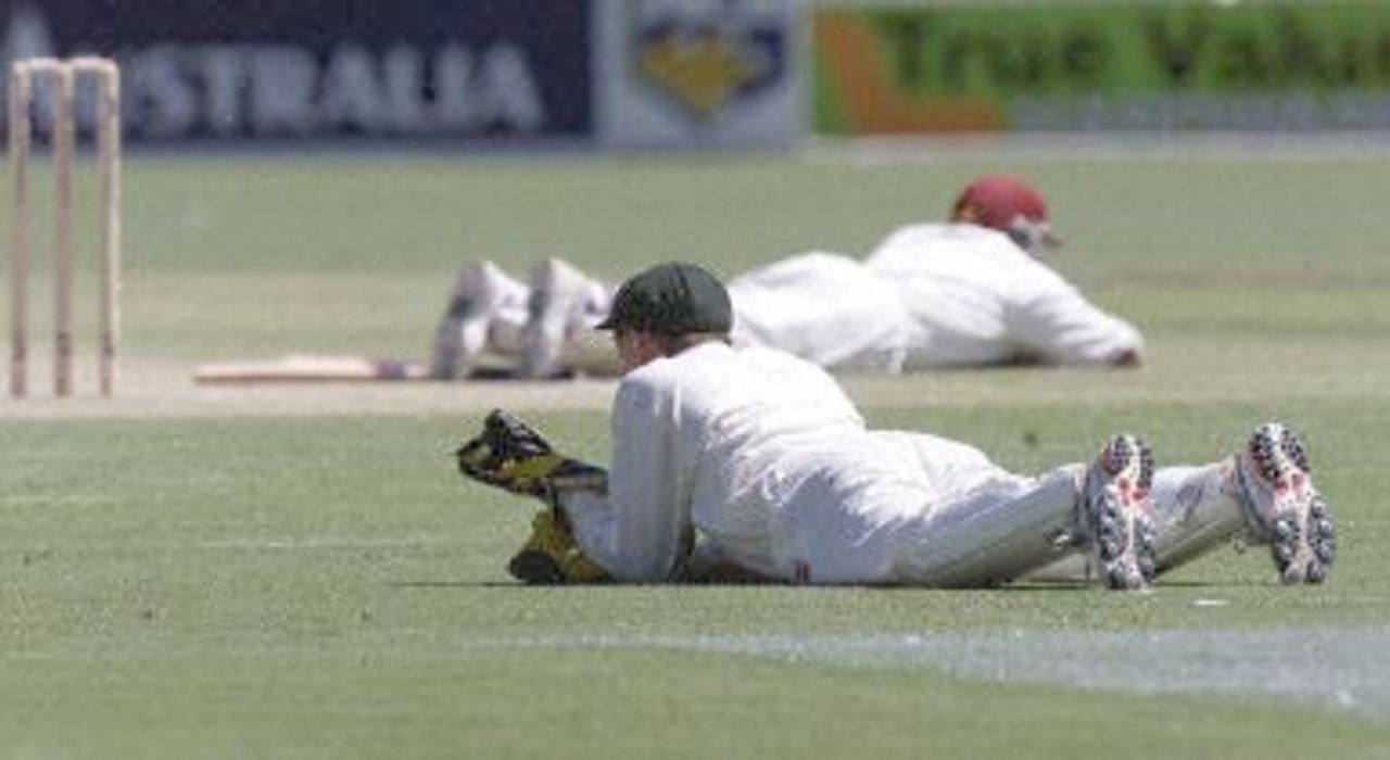 West Indies batsman Brian Lara (top) and Australian wicket-keeper Adam Gilchrist (bottom) lie on the ground as a swarm of locusts passes over Adelaide oval on day two of the third test 16 December 2000. The West Indies at lunch are on 7 for 376, with Lara being dismissed shortly before the break on 182.