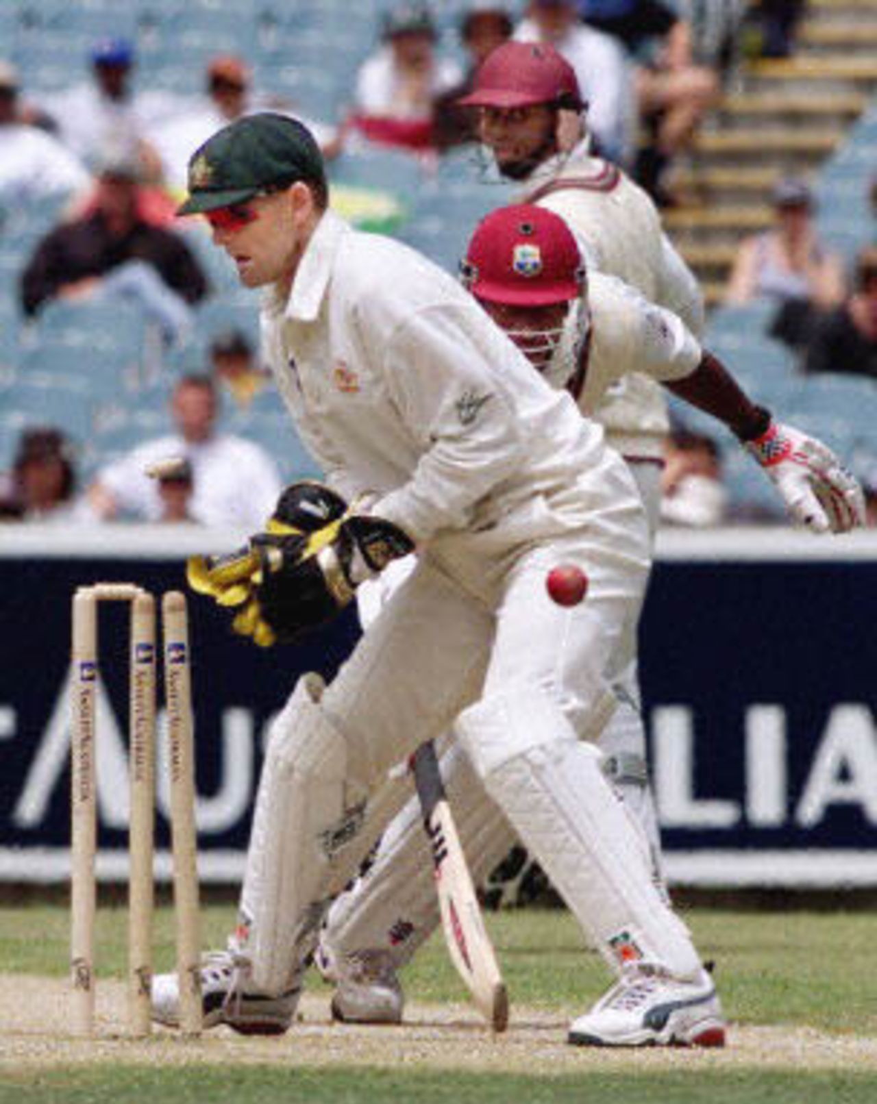 Australian wicketkeeper Adam Gilchrist looks on as a direct throw hits the wickets to run-out West Indian batsman Nixon McLean (C) as his teammate Marlon Samuels looks back to watch the outcome on the fourth day of the fourth Test match at the MCG in Melbourne, 29 December 2000. Once again the West Indies are on the verge of defeat being 78-8 at lunch, still requiring 384 runs for victory.