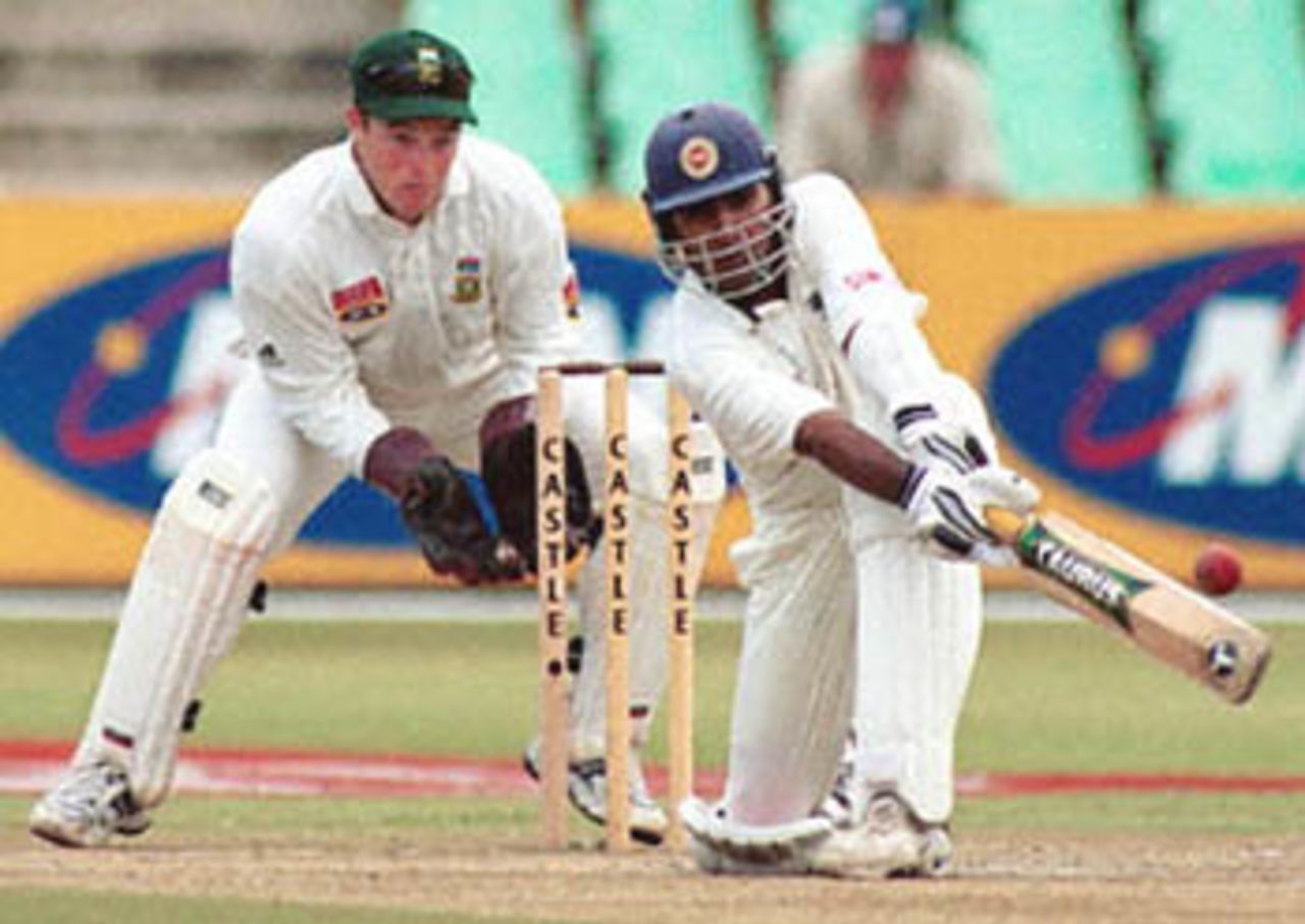 Sri Lankan batsman Mahela Jayawardene plays a sweep shot, 28 December 2000 at Durban's Kingsmead cricket grounds, during the third day of the first Test match between South Africa and Sri Lanka. Jayawardene fell 2 short of his century and was out for 98. Looking on is South African wicket-keeper Mark Boucher.