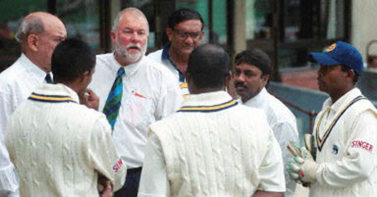Sri Lankan players together with umpires Dave Orchard and Riazuddin (2nd R) discuss the weather interruptions on the fourth day of the first cricket Test match between South Africa and Sri Lanka 29 December 2000 at Durban's Kingsmead cricket grounds. Play was called off due to rain.