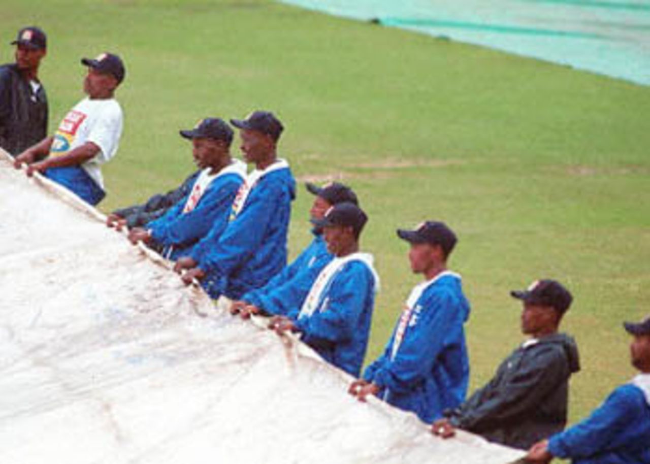 Kingsmead groundsmen put on the covers for the fourth time as rain continues to disrupt the fourth day of the first cricket Test match between South Africa and Sri Lanka 29 December 2000 at Durban's Kingsmead cricket grounds. Play was called of without a ball being bowled due to rain.