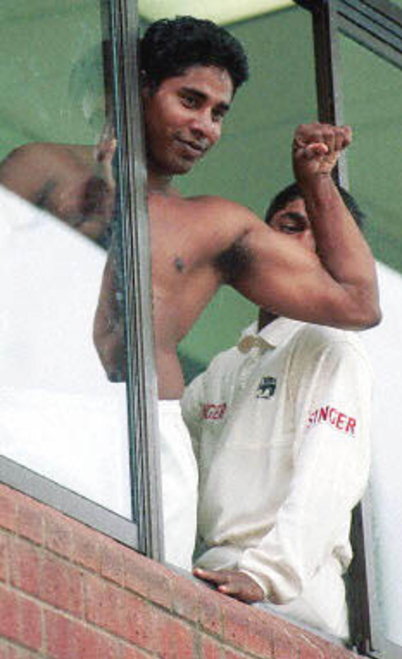 Sri Lankan players Chaminda Vaas shows off his muscles at some female fans as wicket keeper Romesh Kaluwitharana looks on as rain continued to disrupt the 4 day of the first cricket Test match between South Africa and Sri Lanka on 29 December 2000 at Durban's Kingsmead cricket grounds.Play was called of due to rain.