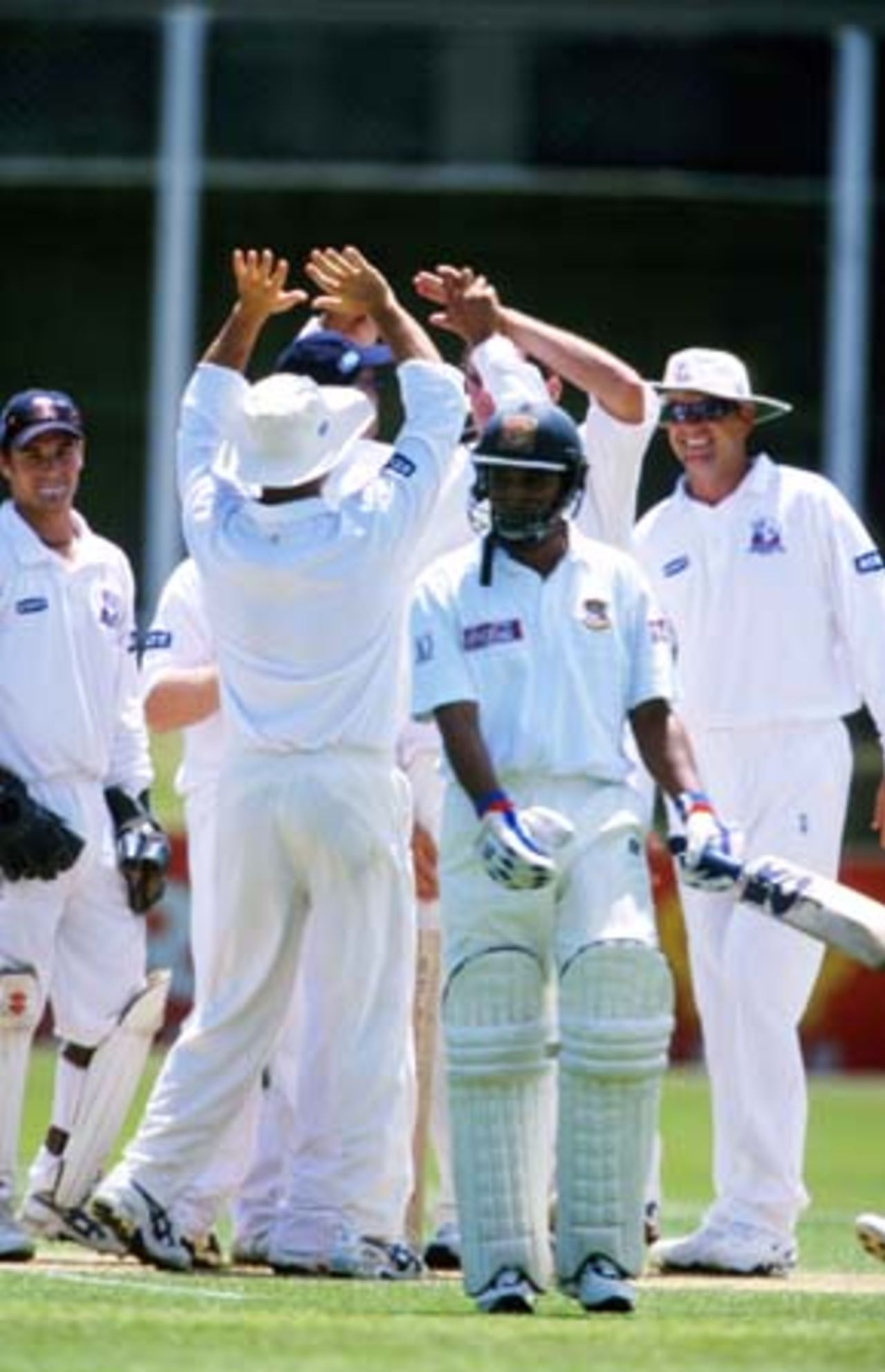 Bangladeshi batsman Habibul Bashar walks off the field after being dismissed bowled by Auckland bowler Kyle Mills for 0. Auckland players celebrate in the background. Tour match: Auckland v Bangladeshis at Eden Park Outer Oval, Auckland, 12-15 Dec 2001 (14 December 2001).