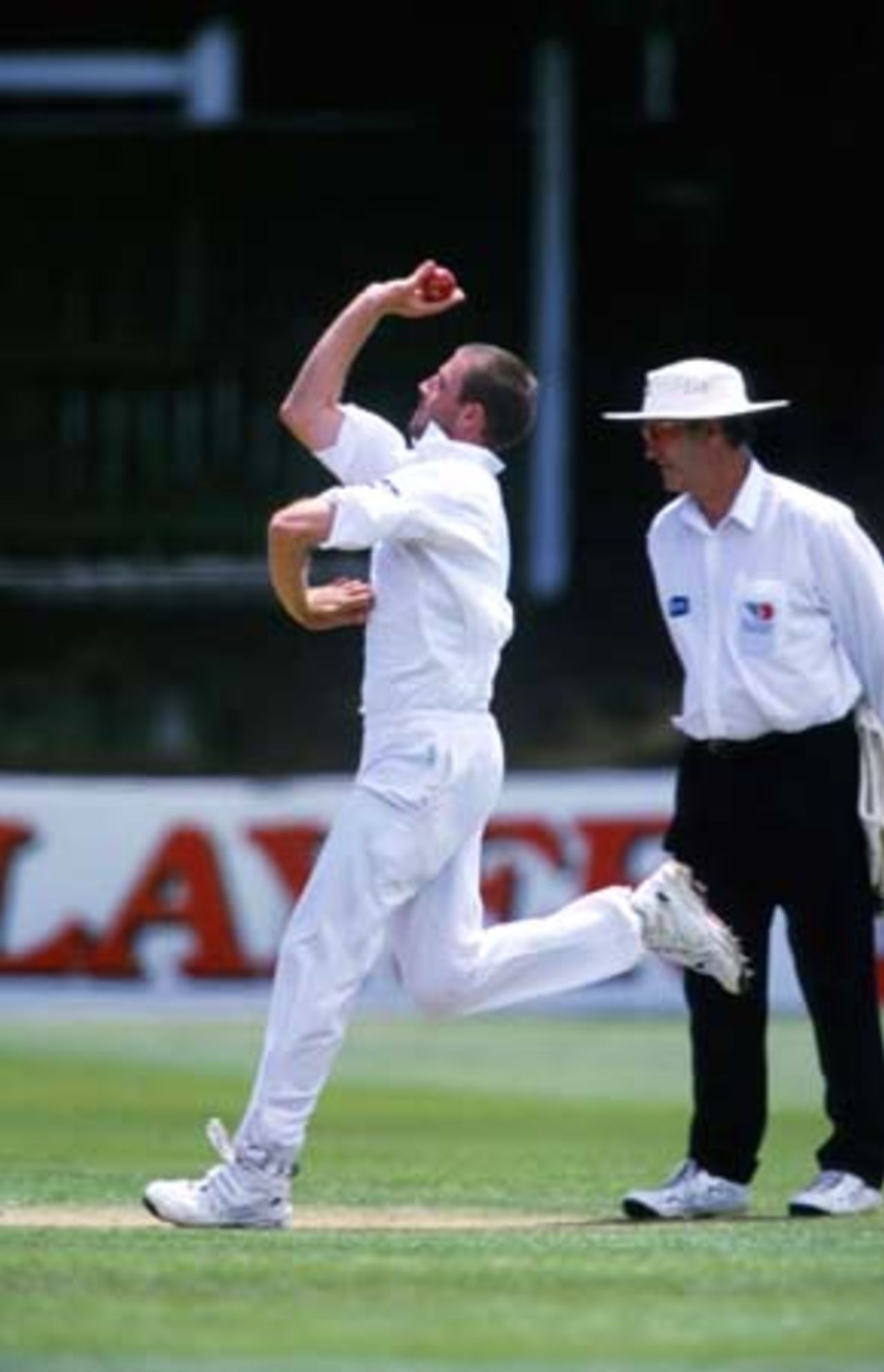 Auckland bowler Chris Drum delivers a ball during his second innings spell of 6-34 from 21.3 overs. Umpire Tony Hill looks on. Tour match: Auckland v Bangladeshis at Eden Park Outer Oval, Auckland, 12-15 Dec 2001 (14 December 2001).