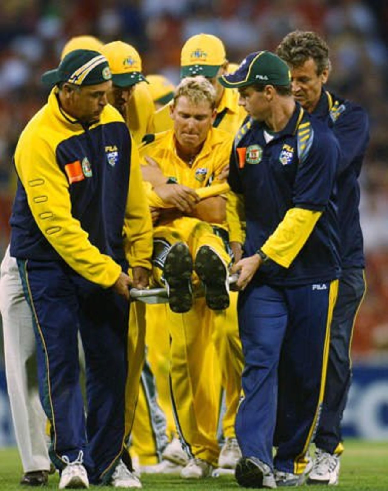 Shane Warne is carried off the field after injuring his shoulder attempting a full-length dive to field the ball during Australia's VB series match with England, Melbourne, 15 Dec 2002