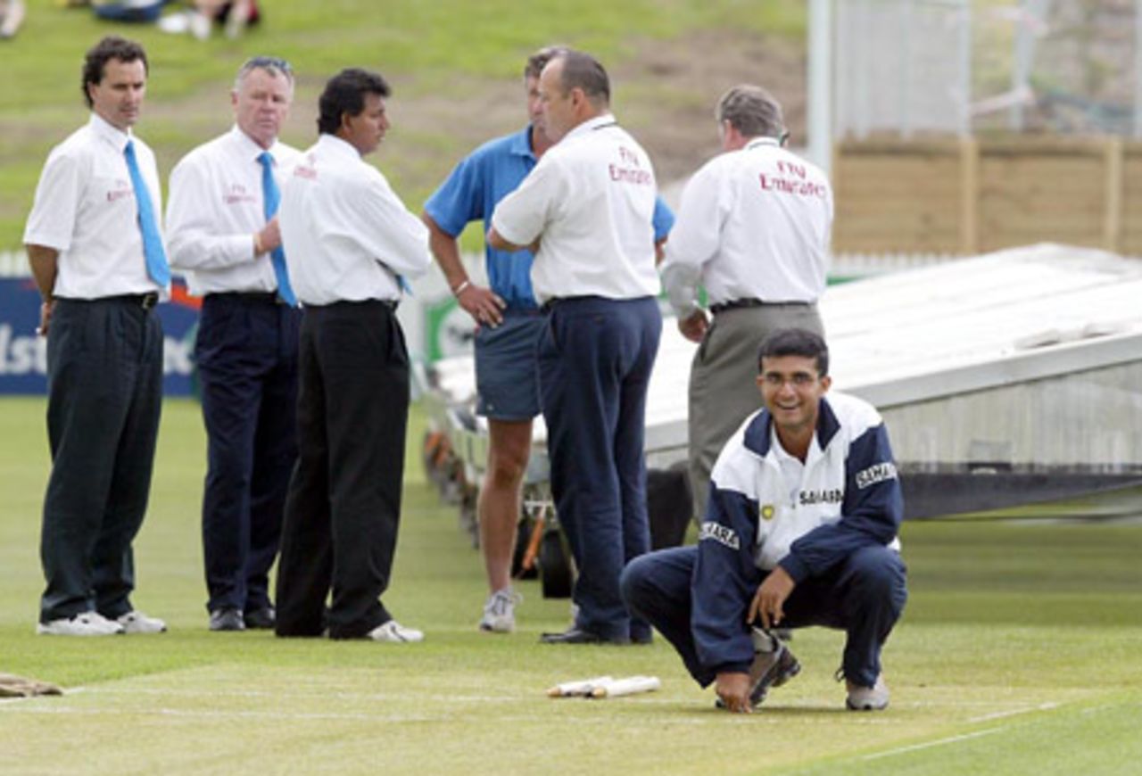 Indian captain Sourav Ganguly checks the condition of the pitch as the start of play is delayed as officials discuss the situation in the background. From left: reserve umpire Brent Bowden, match referee Mike Procter, umpire Asoka de Silva, groundsman Doug Strachan (obscured), umpire Daryl Harper and TV umpire Doug Cowie (facing away). Play was eventually abandoned on day one. 2nd Test: New Zealand v India at Westpac Park, Hamilton, 19-23 December 2002 (19 December 2002).
