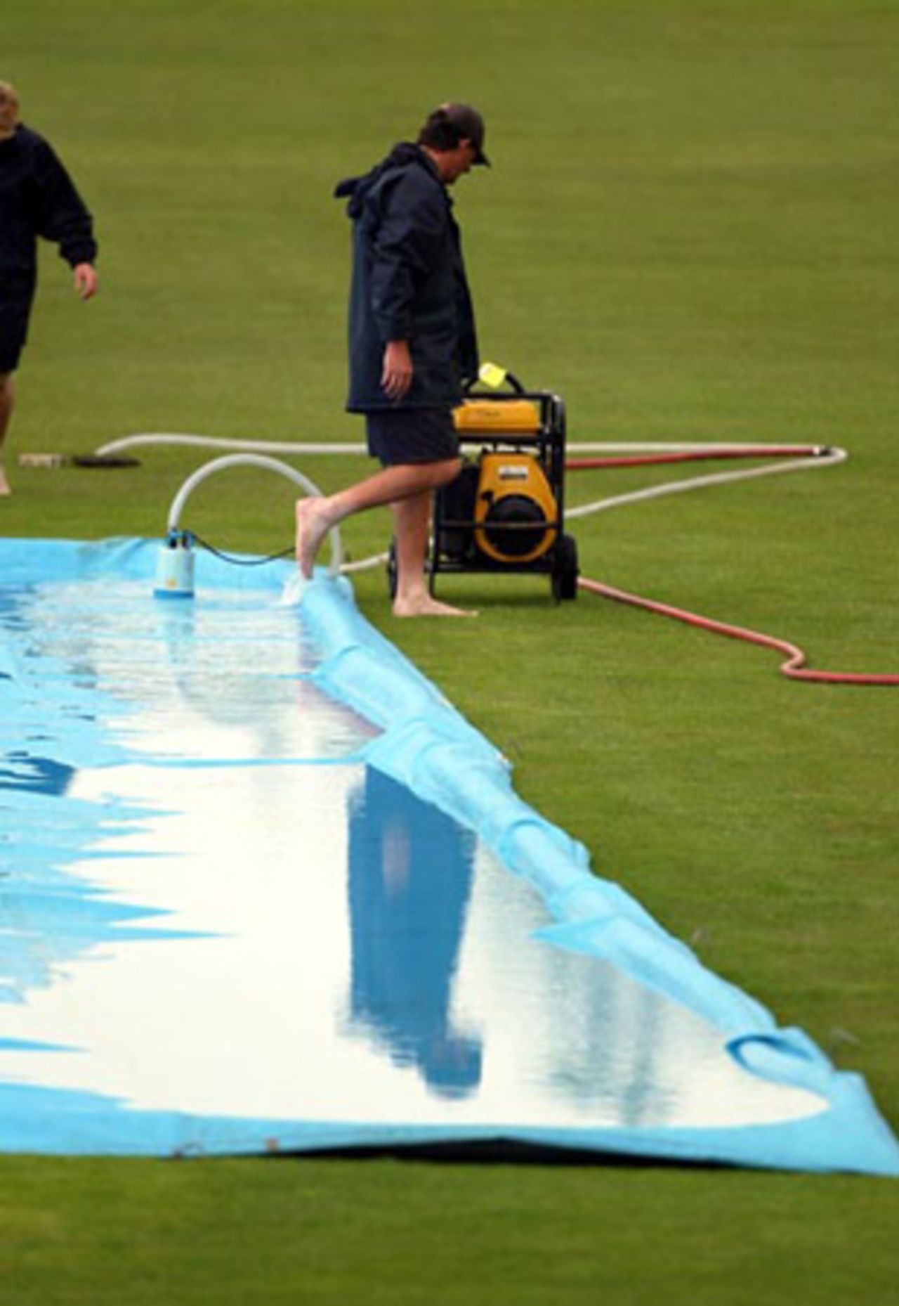 A member of the ground staff sets up a pump to remove excess water from the covers after a rain shower. Play was eventually abandoned on day one at 2.45pm. 2nd Test: New Zealand v India at Westpac Park, Hamilton, 19-23 December 2002 (19 December 2002).