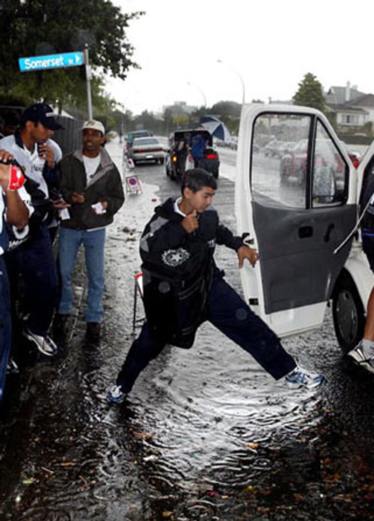 Indian player Parthiv Patel jumps over a puddle to get into the team bus as he leaves the ground. Team-mate Rahul Dravid (left) looks on. 2nd Test: New Zealand v India at Westpac Park, Hamilton, 19-23 December 2002 (19 December 2002).