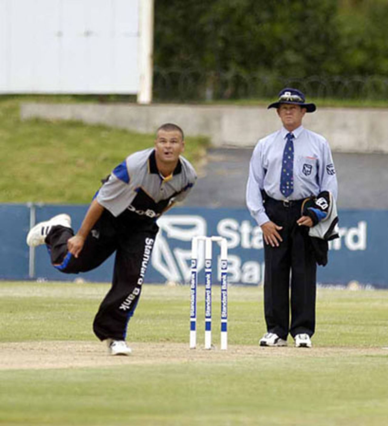 Charl Langeveldt follows through against Nashua WP with umpire Brian Jerling looking on