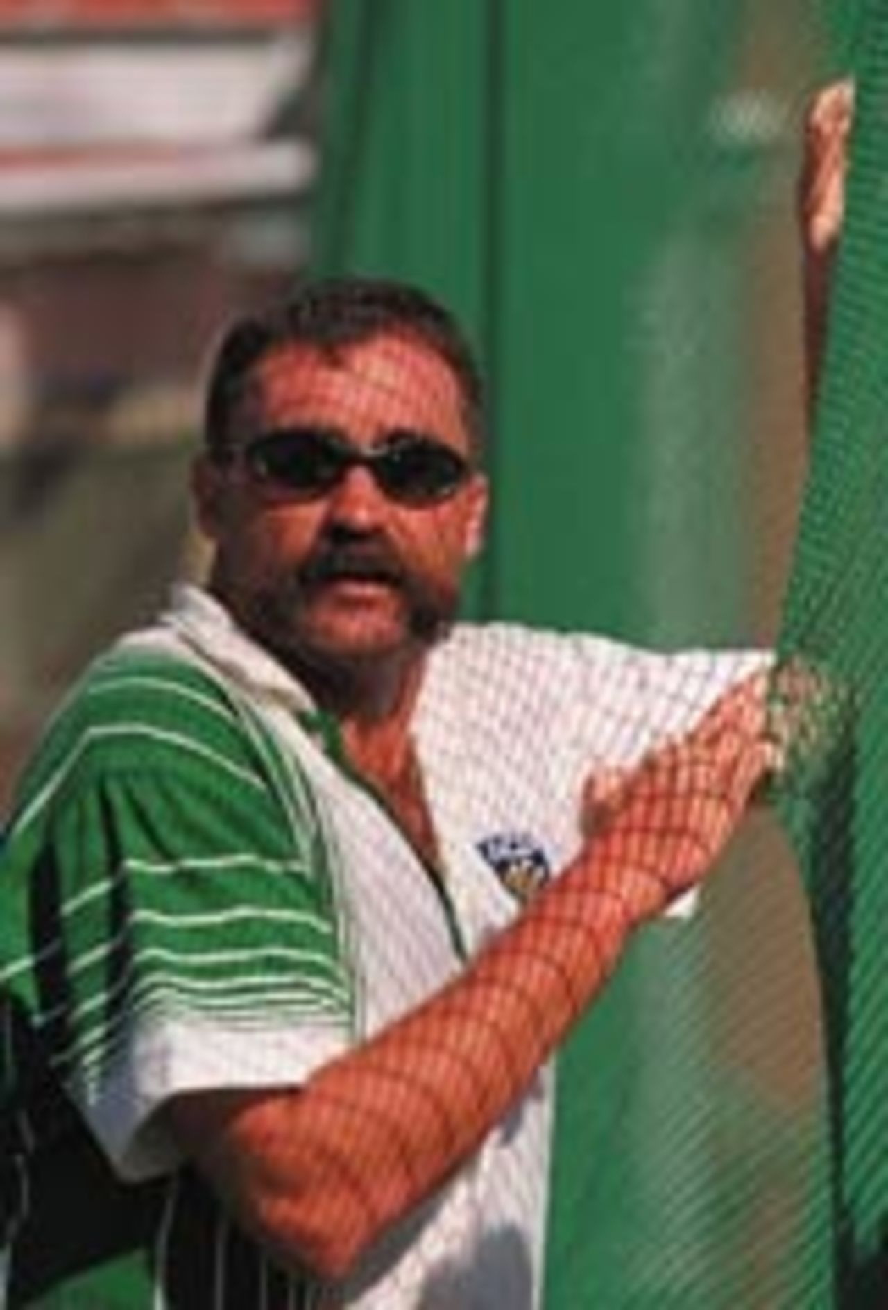 BOWLER MERV HUGHES OF AUSTRALIA WATCHES THROUGH THE NETTING AS HIS TEAM , AUSTRALIAN XI, PRACTICE IN THE NETS TODAY BEFORE THE ONE DAY INTERNATIONAL AGAINST ENGLAND IN MELBOURNE.