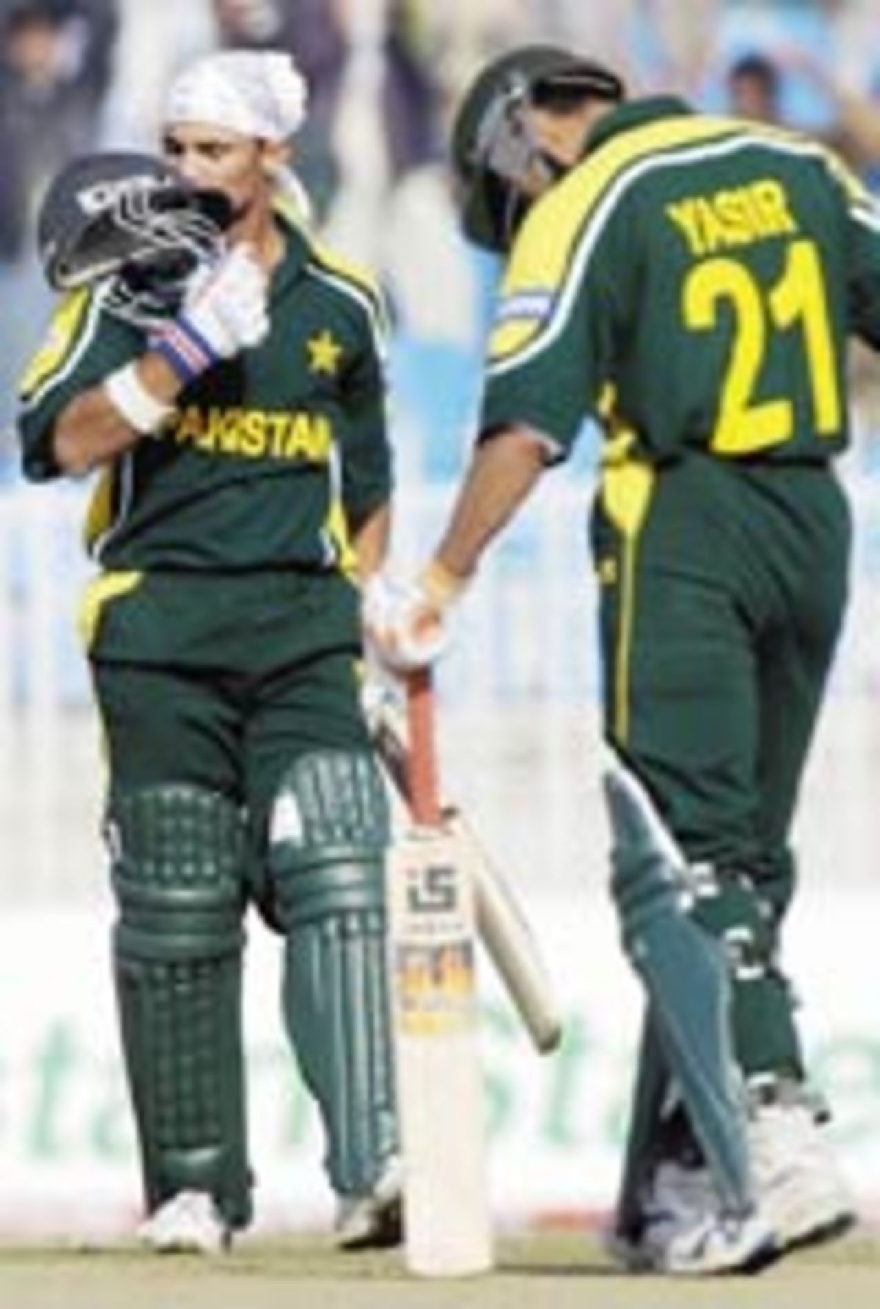 Pakistani batsman Imran Farhat (L) kisses his helmet as his mate Yasir Hameed moves forward to congratulate him after he completed a century during the final One Day International (ODI) cricket match between Pakistan and New Zealand in Rawalpindi, 07 December 2003.