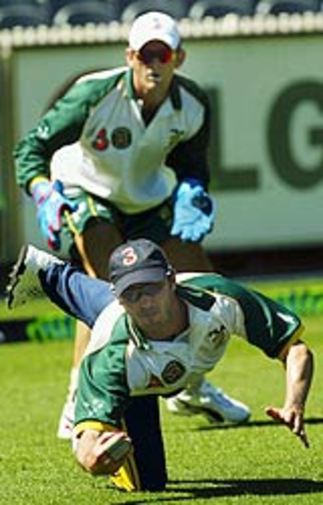 Damien Martyn dives during fielding practice as Adam Gilchrist looks on, Melbourne, December 24, 2003