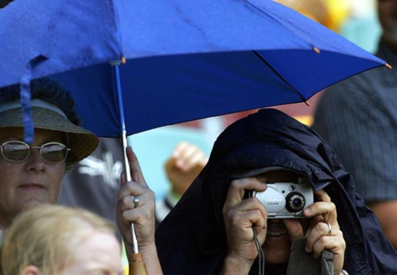 A spectator under a blue umbrella during the rain break at Brisbane, Australia v New Zealand, 3rd ODI, December 10, 2004