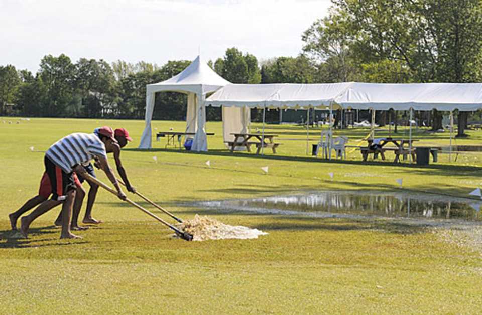 Groundsmen work to remove water from the ground