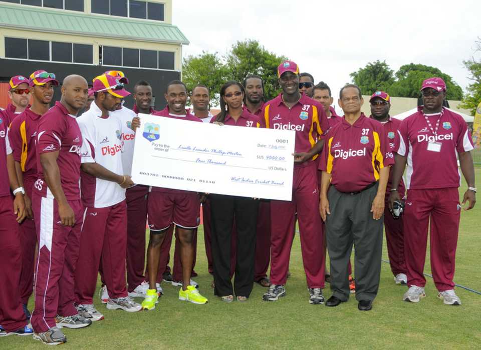 The West Indies team hand over a cheque to Runako Morton's widow