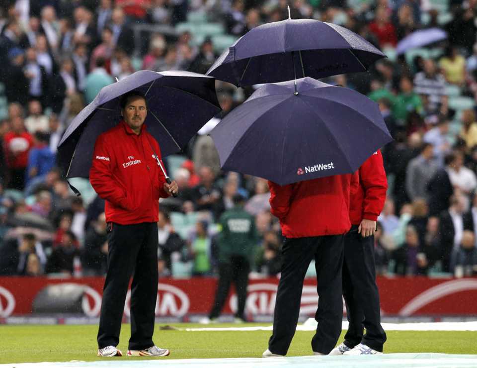 The umpires take cover from the rain
