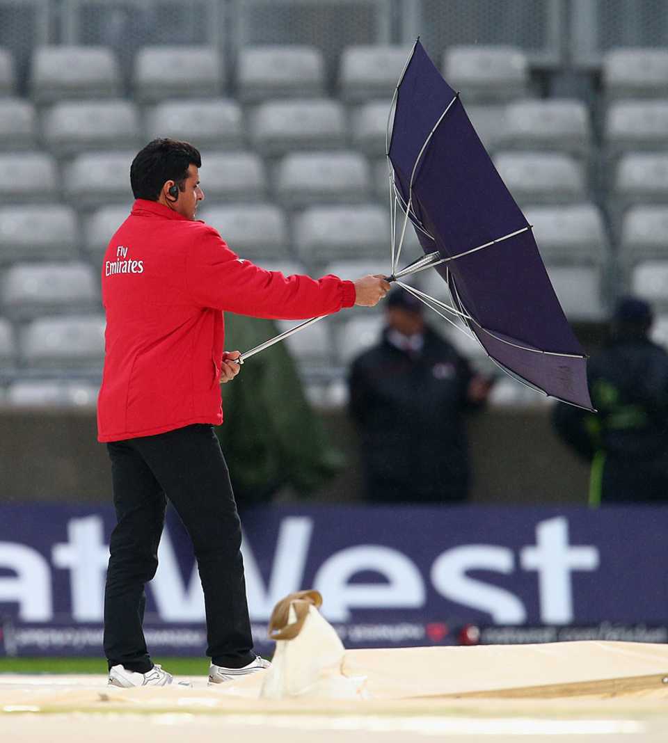 Aleem Dar struggles to keep hold of his umbrella
