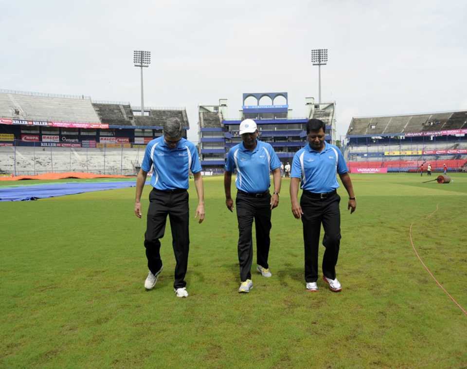 The umpires inspect the wet outfield
