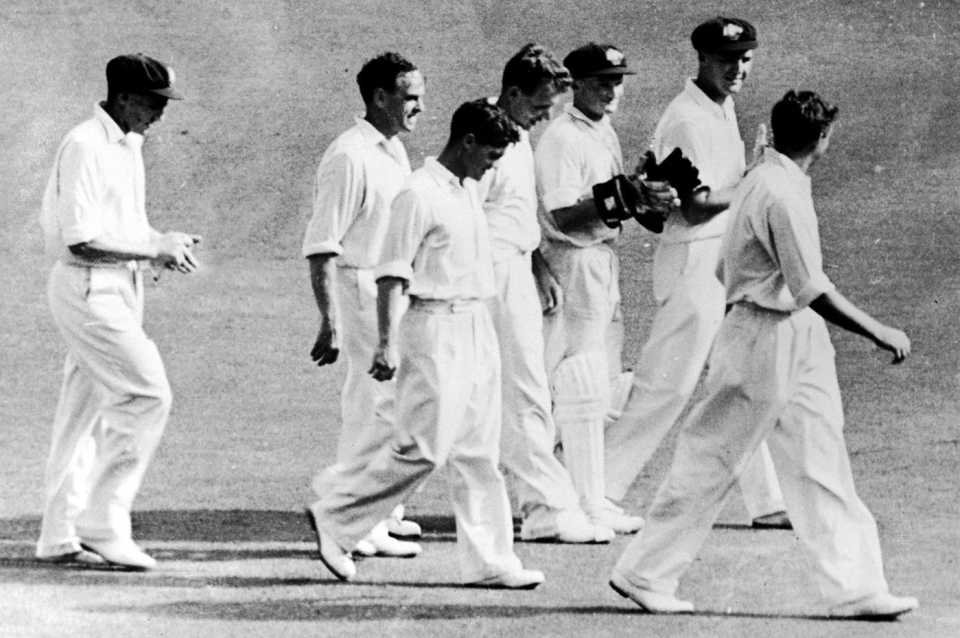Ray Lindwall walks off with his team-mates after getting 100 Test wickets