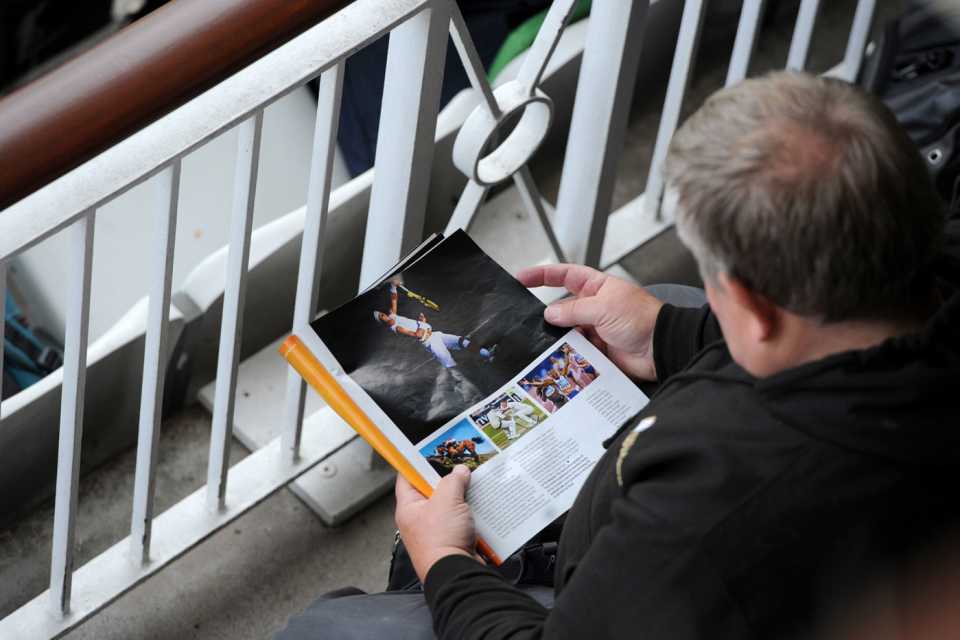 A cricket fan reads a magazine