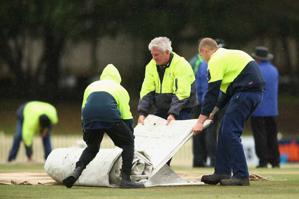 Groundsmen unfold the covers as rain falls, South Australia v Tasmania, Sydney, October 15, 2014