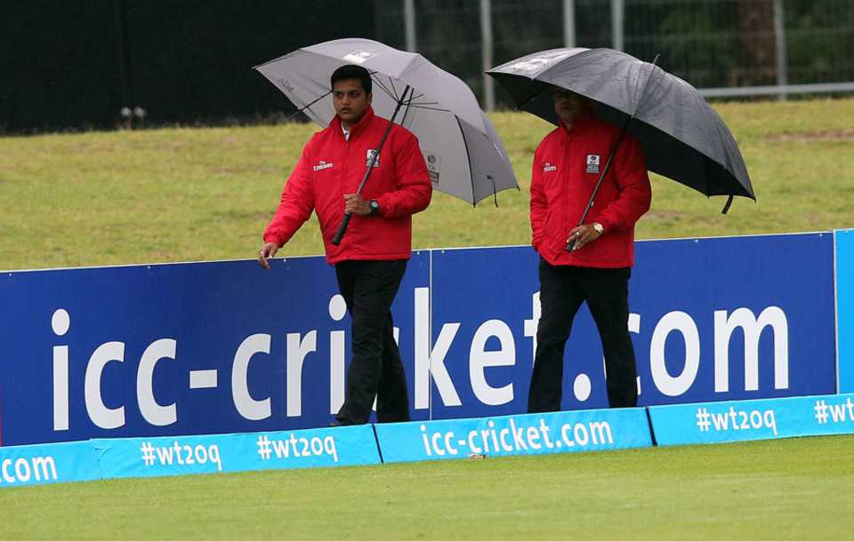 The umpires inspect the wet outfield