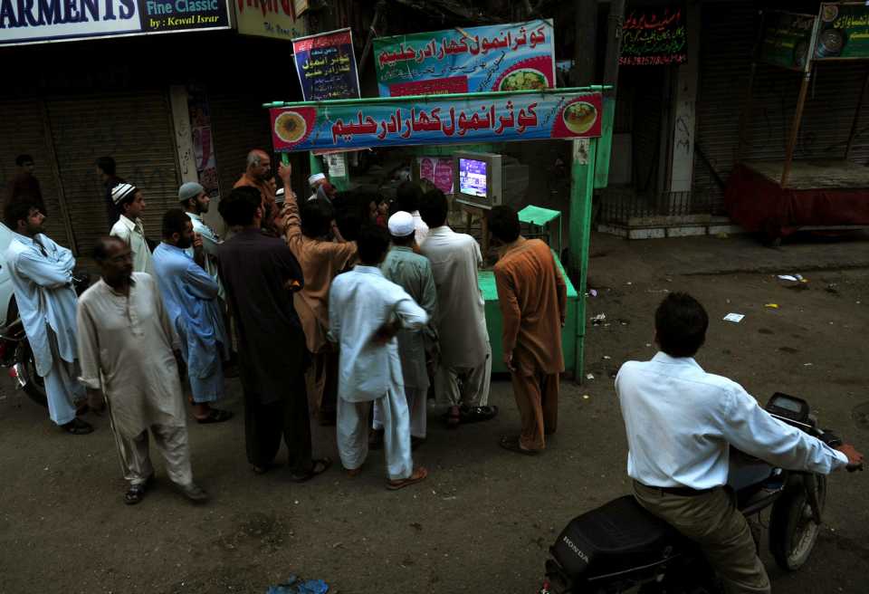 Pakistani fans gather to watch a match between Pakistan and India on a television set on a street in Karachi