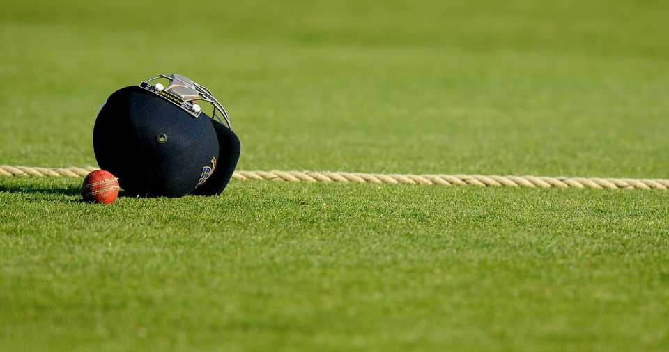 The old ball and a player's helmet lie next to the boundary rope