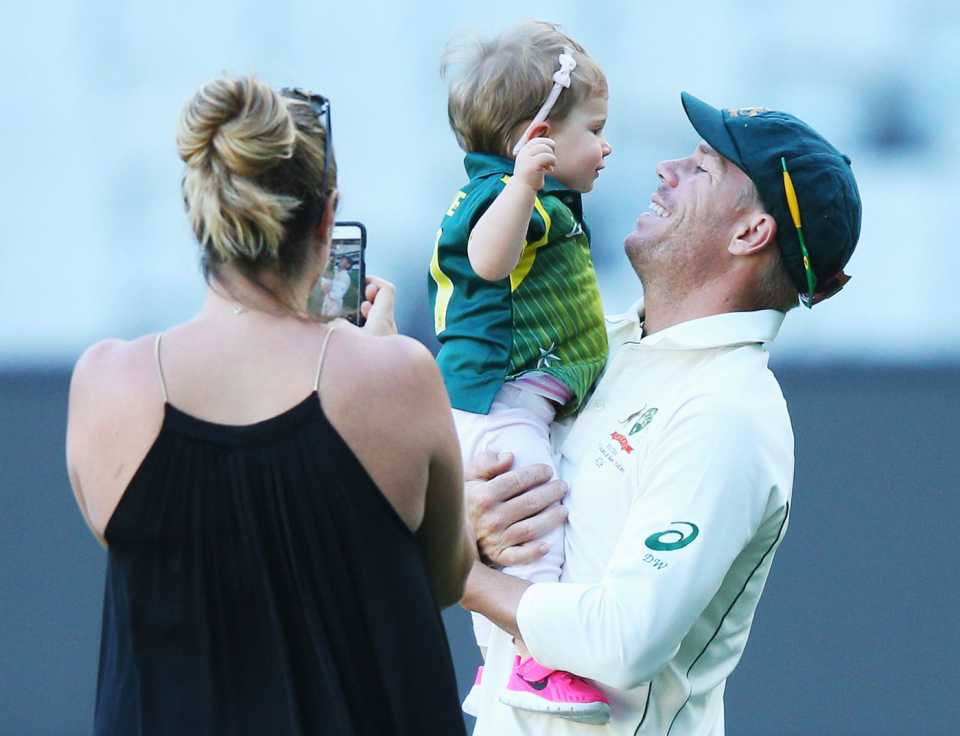 David Warner plays with his daughter Ivy while his wife, Candice, takes a photo of them