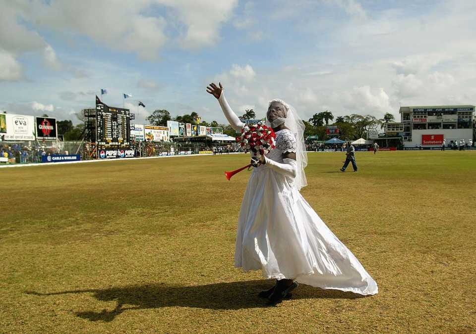 A man dressed as a bride walks around the ground