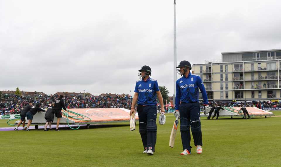 Joe Root and Jason Roy leave the field as the covers come on for the final time