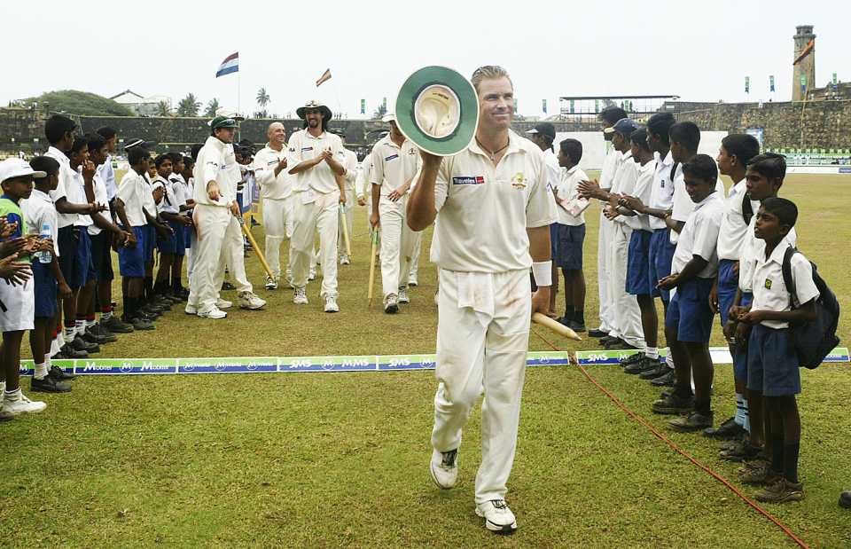 Shane Warne is cheered on by schoolkids as he leads the team off the field after his ten-for