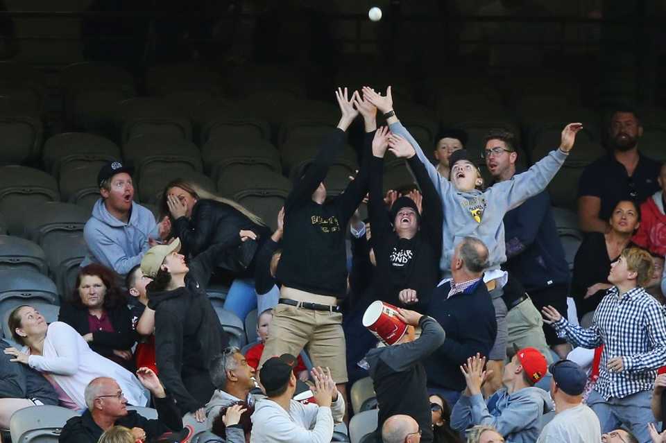 Enthusiastic fans try to catch the ball after it is sent into the stands