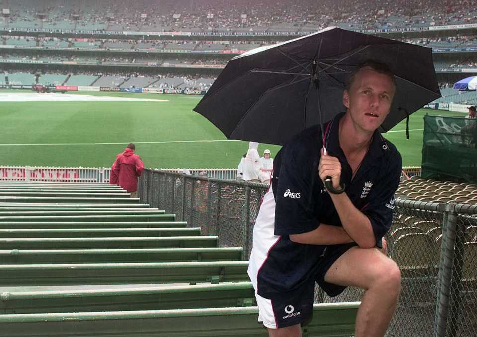 Alan Mullally takes cover under an umbrella, Australia v England, Carlton and United Series, 2nd final, Melbourne, February 12, 1999