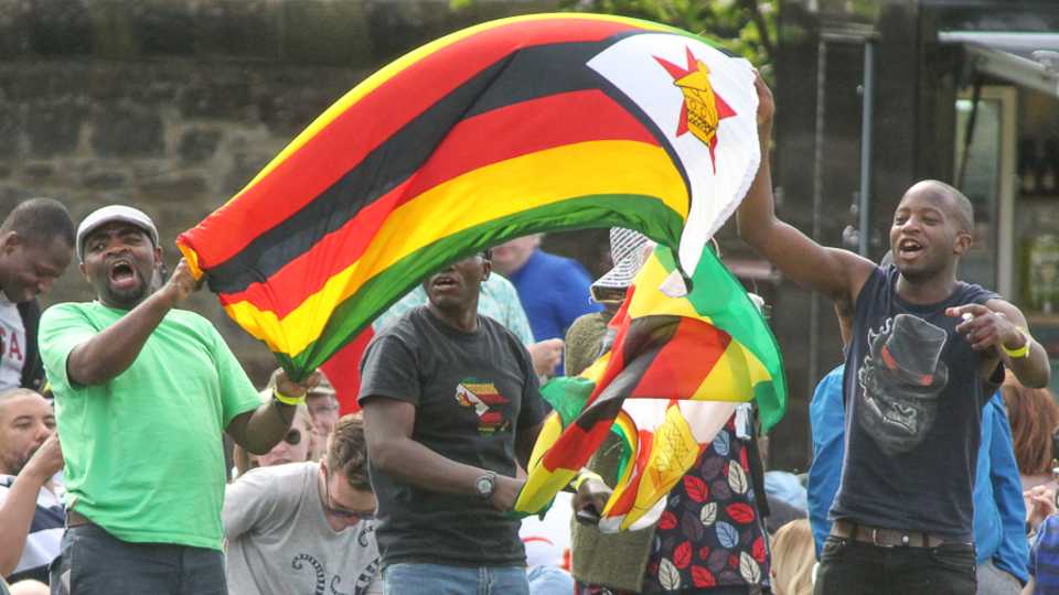 Visiting fans unfurl the Zimbabwe flag after victory is secured