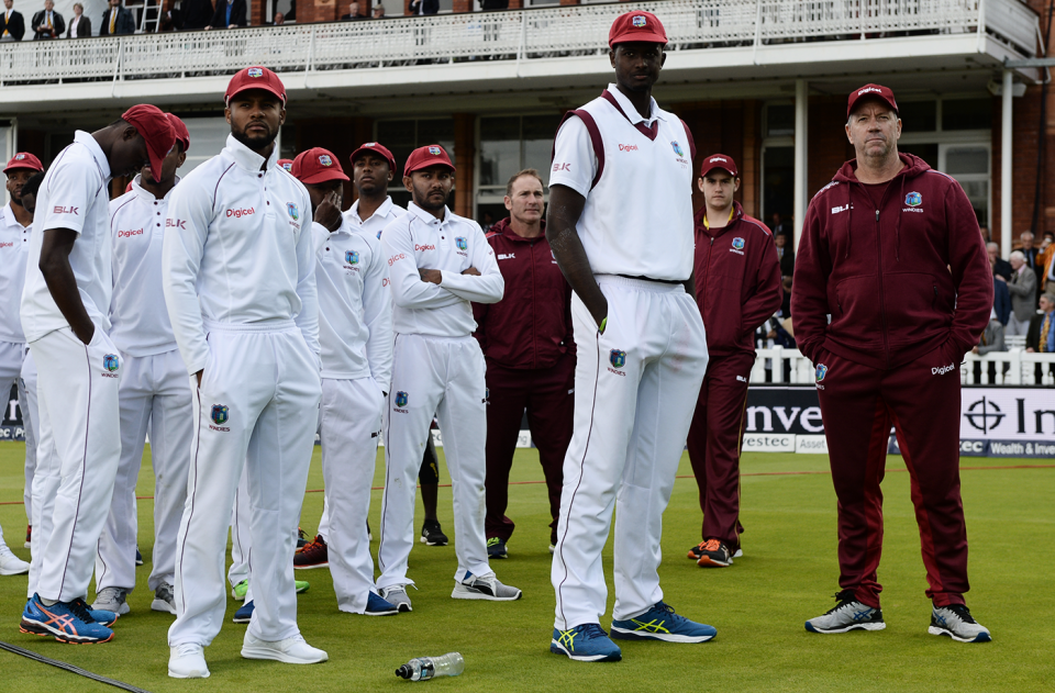 West Indies' players stand on the field with their coach Stuart Law at the end of the game