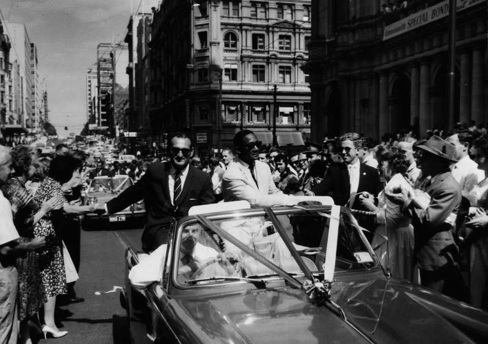 Gerry Gomez and Frank Worrell sit in an open-top car and drive through the streets of Melbourne greeting fans who came to see off the West Indies side at the end of the tour, February 20, 1961