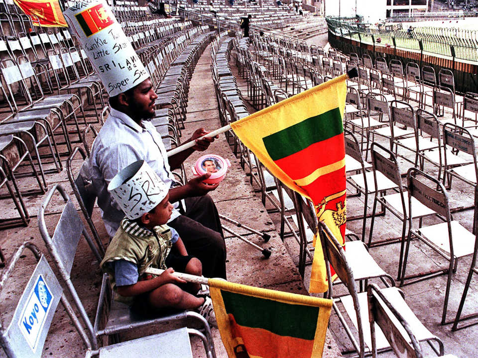 Two spectators sit in a virtually empty stand at the Premadasa