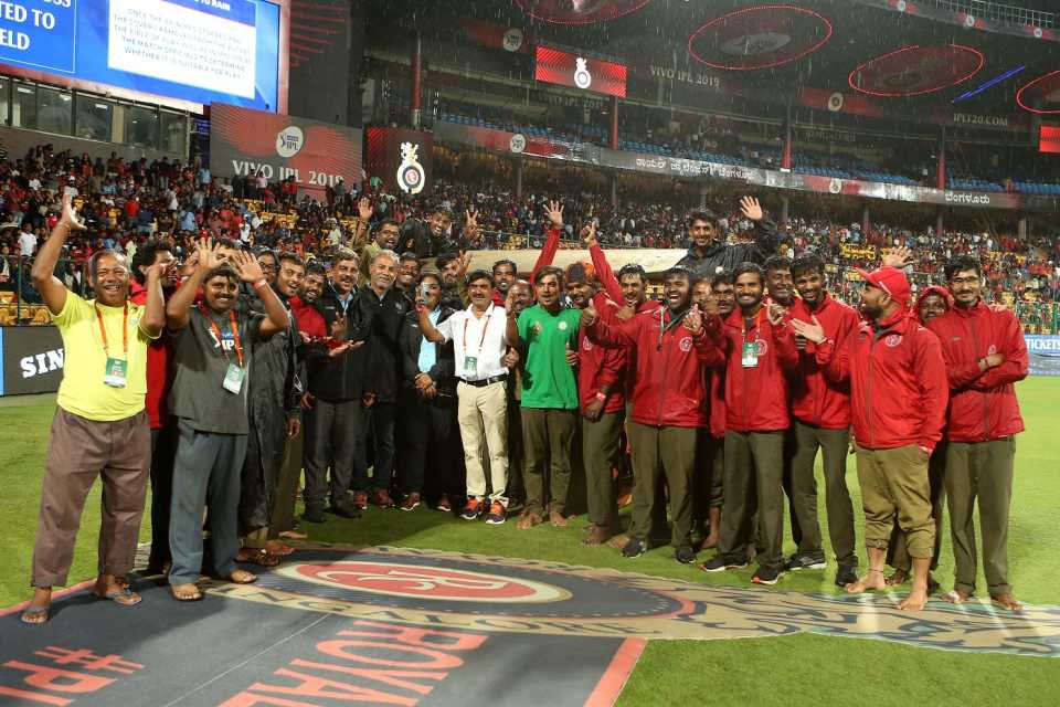 The groundstaff in Bengaluru pose for a photo while rain pounds the M Chinnaswamy Ground