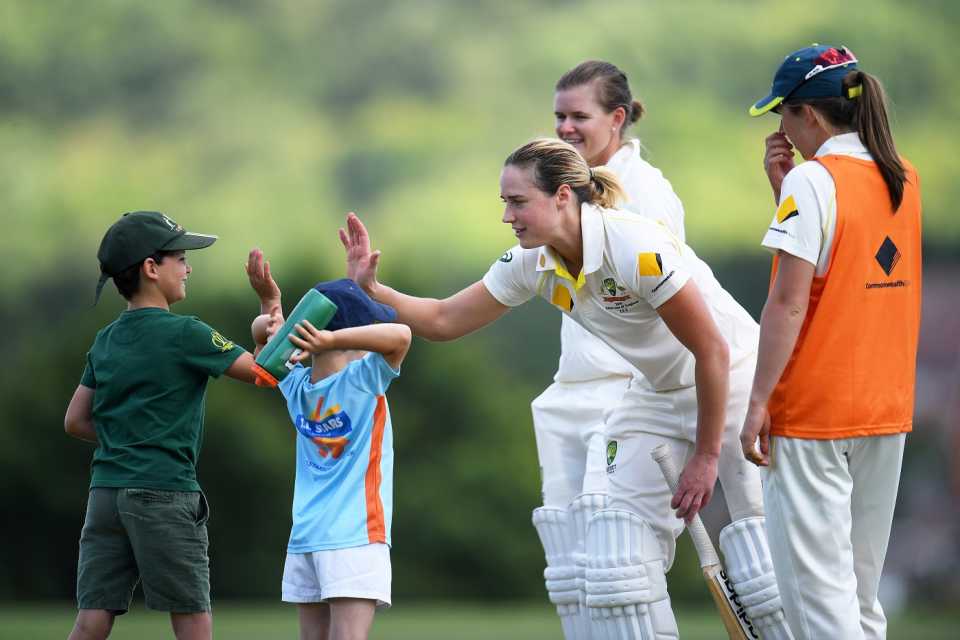 Ellyse Perry interacts with a couple of young fans during a drinks break
