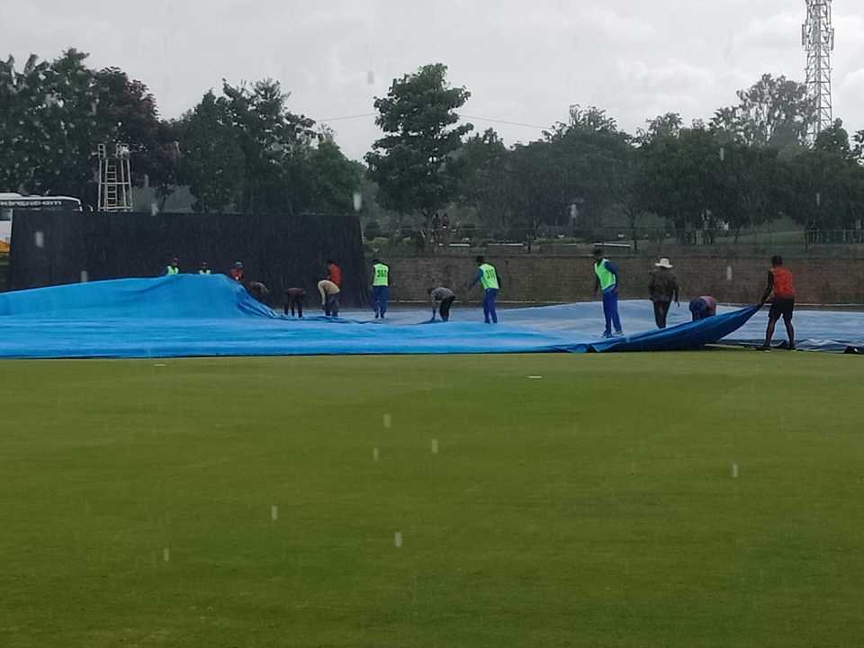 Mumbai players help the groundstaff with the covers