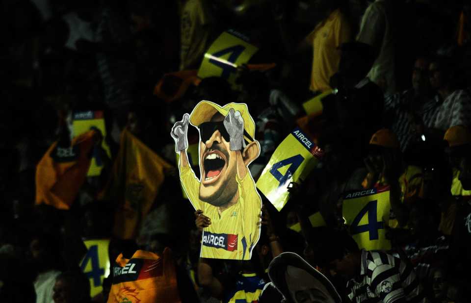A spectator holds up a cutout of MS Dhoni
