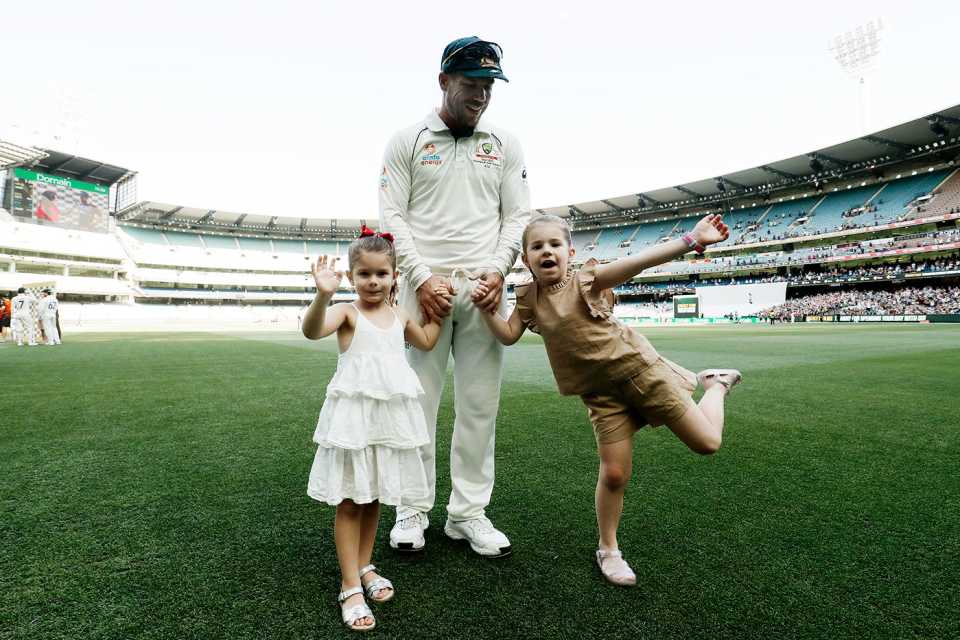 David Warner walks along the ground with his daughters