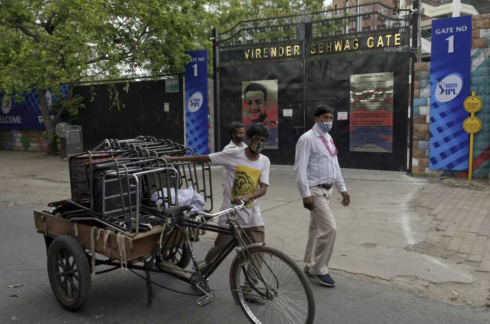 A worker packs up and carries away chairs on a cycle rickshaw after the IPL was suspended