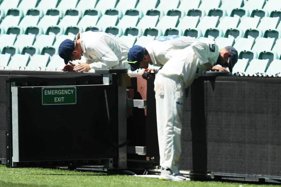 Daniel Hughes, Mitchell Starc and Nathan Lyon look for a lost ball