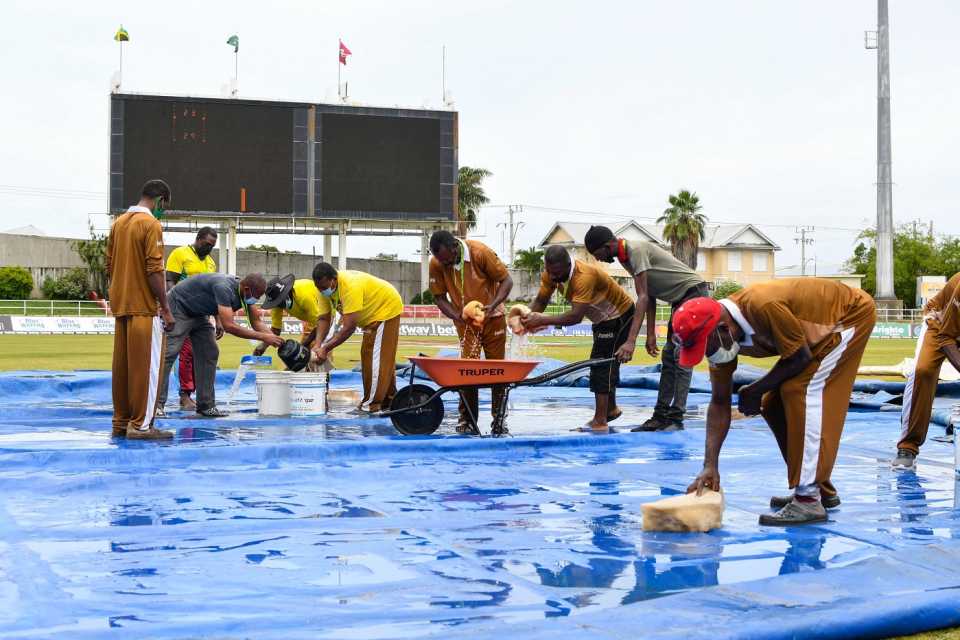 The ground staff at Sabina Park mop up water from the covers