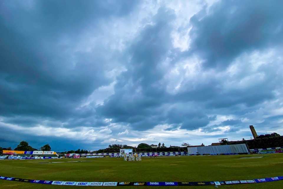 Clouds paint the sky with players on the field at Galle