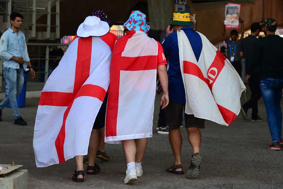 England fans with flags wrapped around them arrive at the stadium